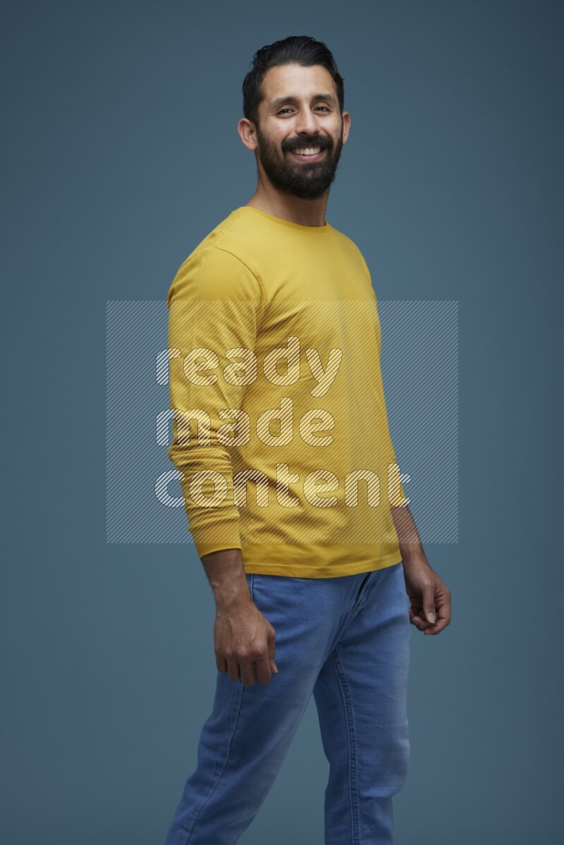 Man posing in a blue background wearing a yellow shirt