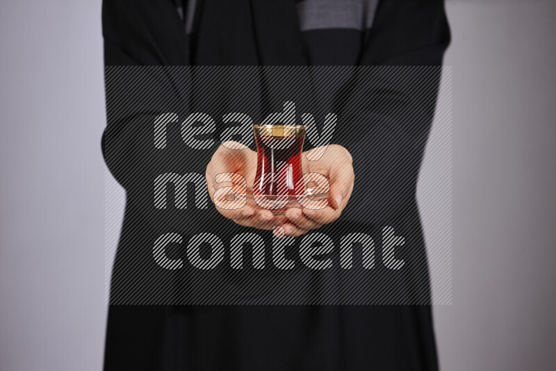 A woman in black abaya holding different glassware in different positions