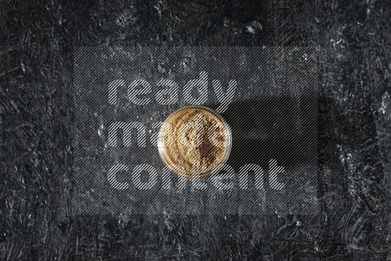 وعاء زجاجي ممتلئ ببودرة بهار الفلفل الحلو على خلفية سوداء