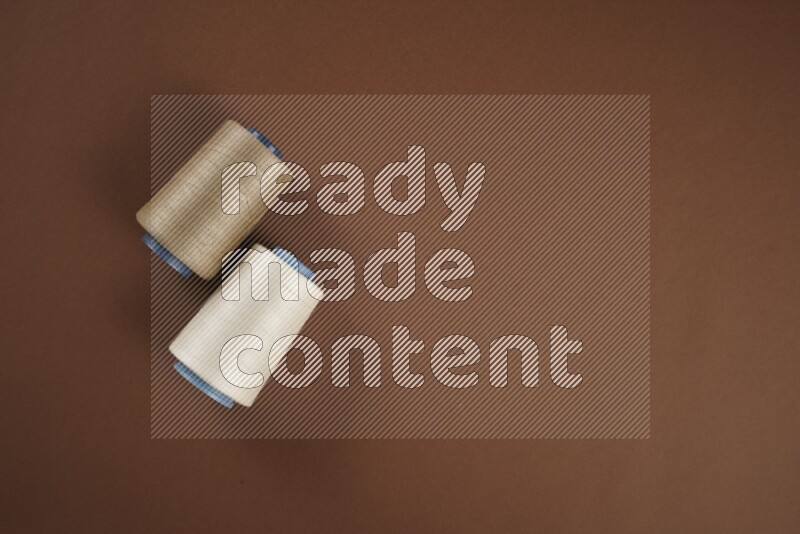 A white and brown collection of sewing and tailoring tools arranged on a brown background