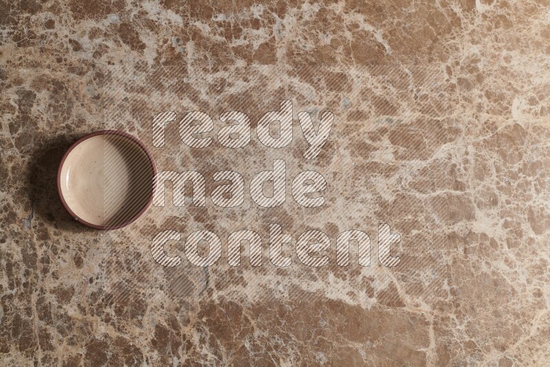 A beige pottery oven plate on beige marble background