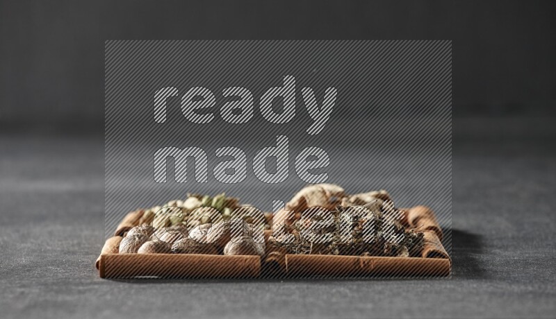 4 squares of cinnamon sticks full of dried basil, cardamom, dried ginger and nutmegs on black flooring
