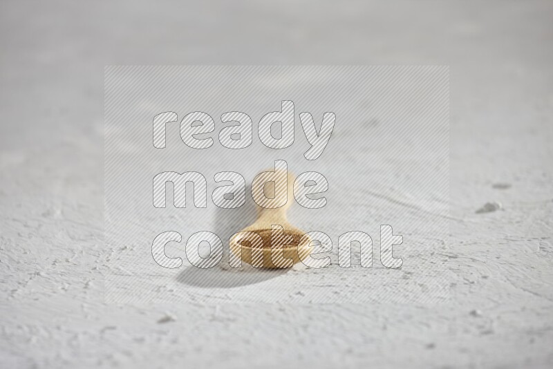 Cinnamon powder in a wooden spoon on a white background