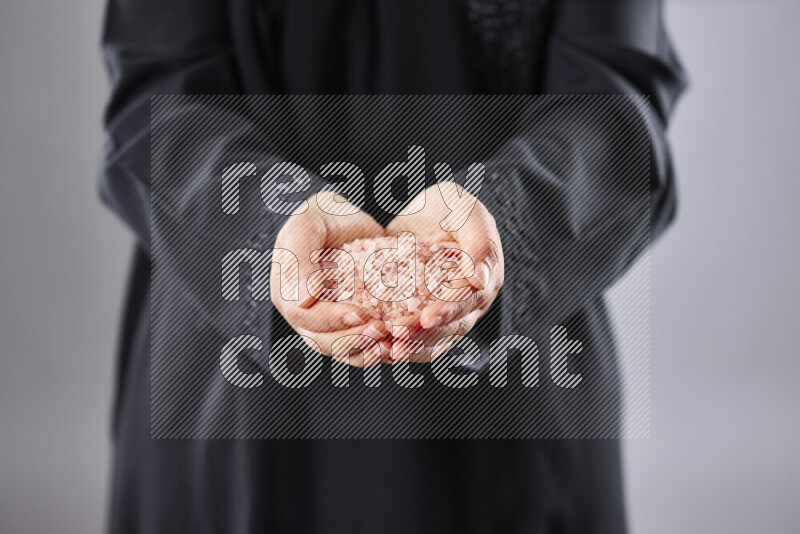 Woman in abaya holding different kinds of spices in different positions