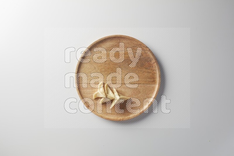 Three Sambosas on a wooden round plate on a white background
