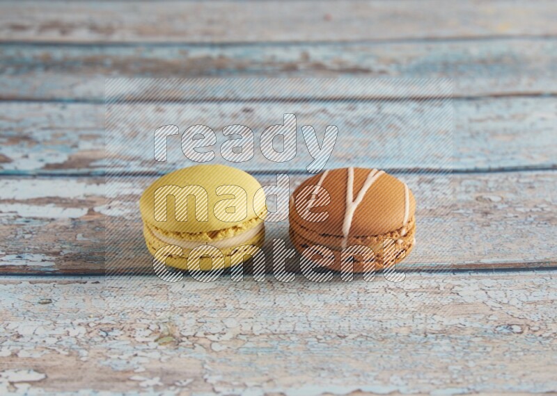 45º Shot of of two assorted Brown Irish Cream, and Yellow Lime macarons on light blue background