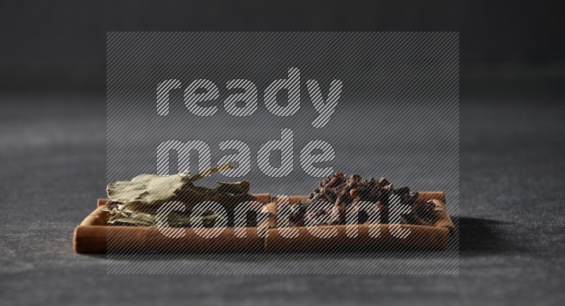 2 squares of cinnamon sticks full of cloves and bay laurel leaves on black flooring