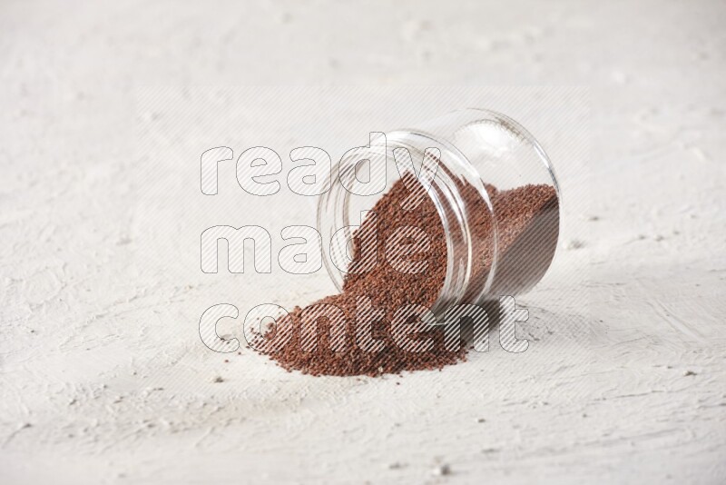 A glass jar full of garden cress seeds and jar is flipped and seeds are spread on a textured white flooring
