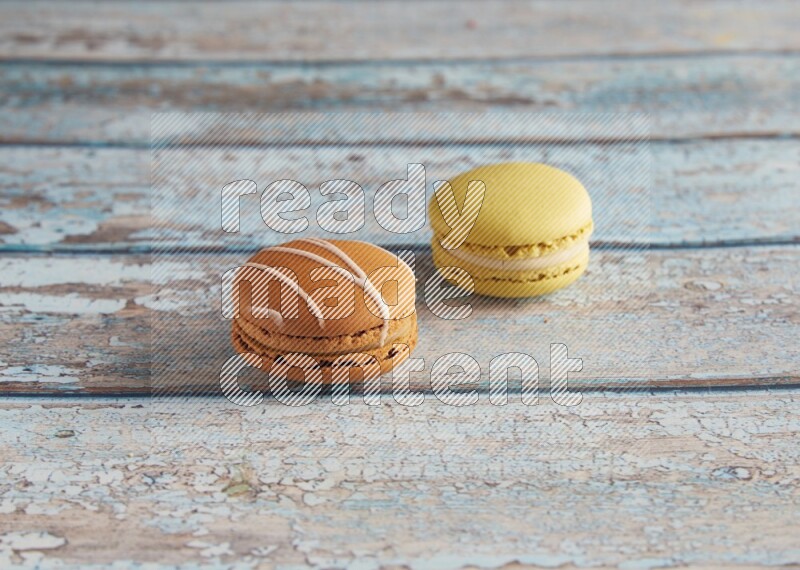 45º Shot of of two assorted Brown Irish Cream, and Yellow Lime macarons on light blue background