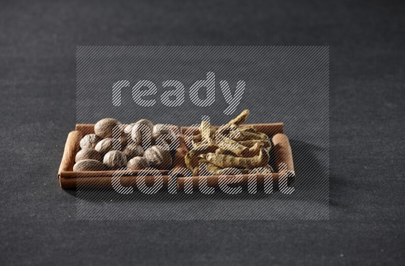 2 squares of cinnamon sticks full of nutmeg and turmeric fingers on black flooring