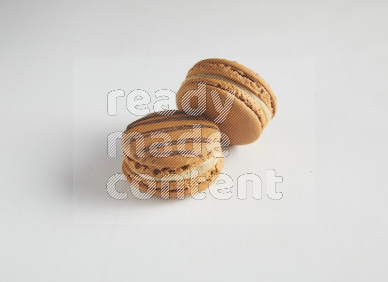 45º Shot of two light brown  Almond Cream macarons on white background