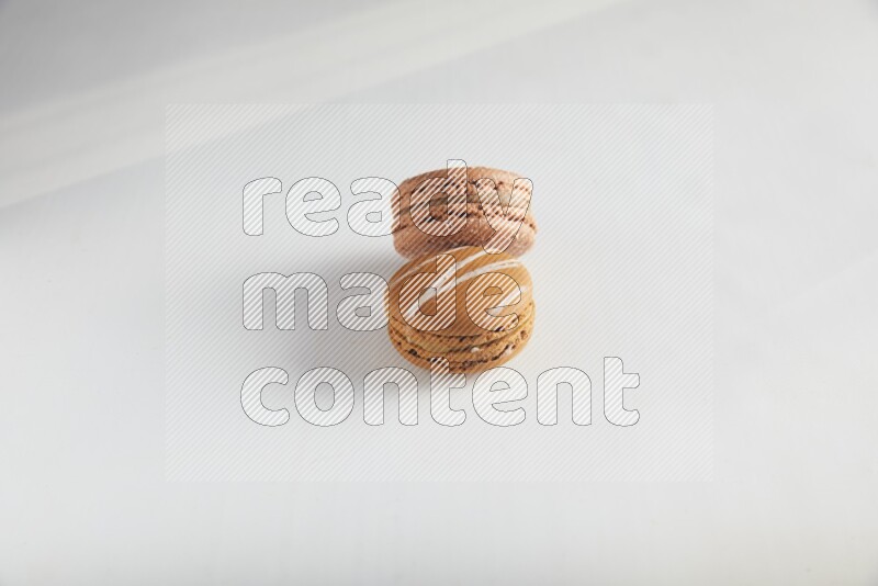 45º Shot of of two assorted Brown Irish Cream, and Brown Hazelnuts macarons on white background