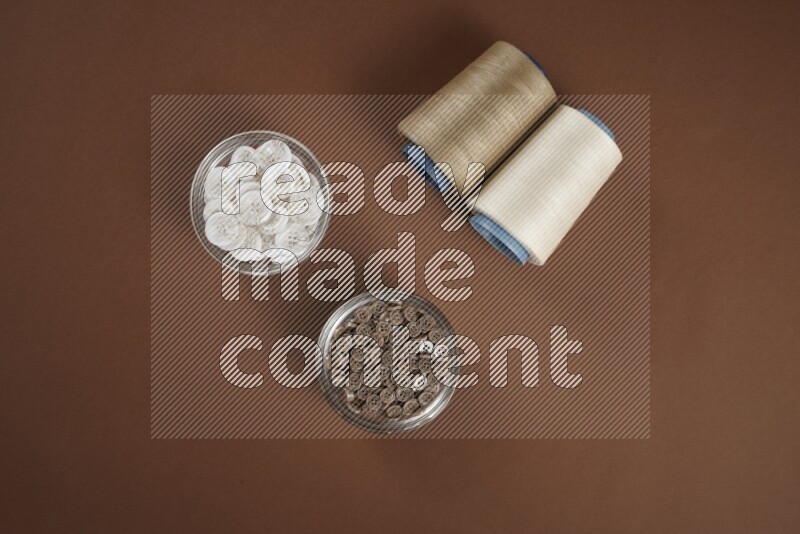 A white and brown collection of sewing and tailoring tools arranged on a brown background