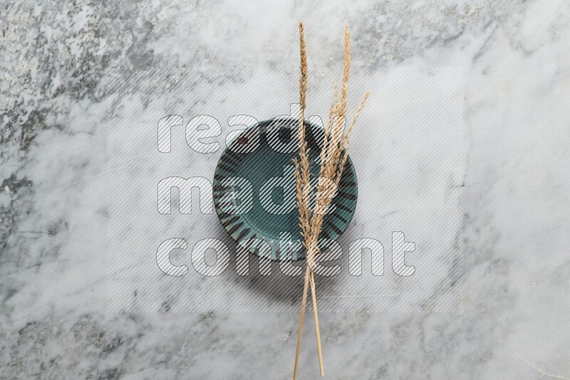Wheat stalks on multicolored pottery plate on grey marble background