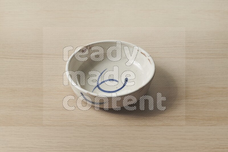 A multicolored pottery bowl on light wooden background