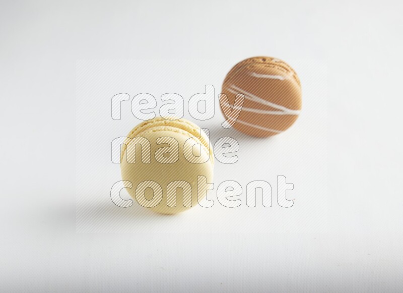 45º Shot of of two assorted Brown Irish Cream, and Yellow Vanilla macarons on white background