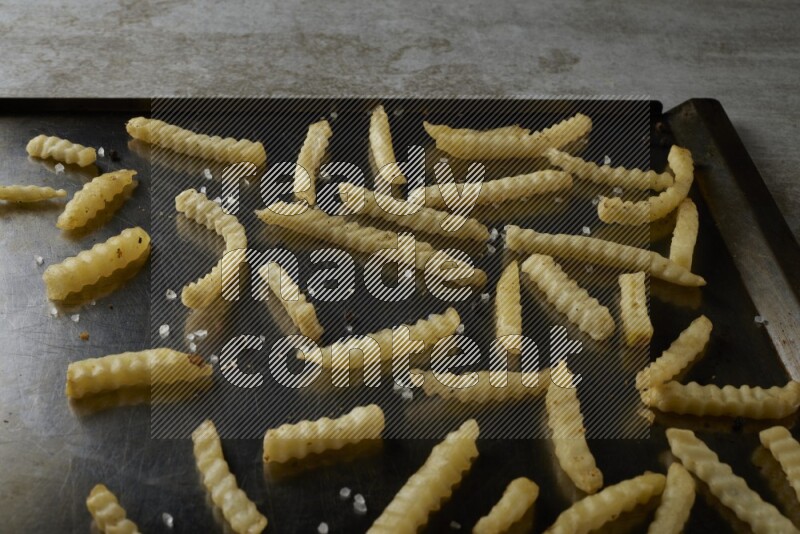 crinkle fries in a black stainless steel rectangle tray on grey textured counter top