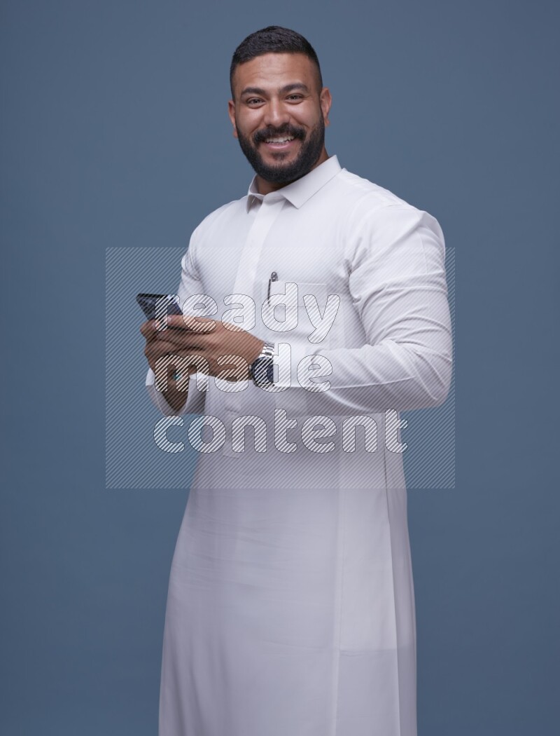 A man Texting on Blue Background wearing Saudi Thob