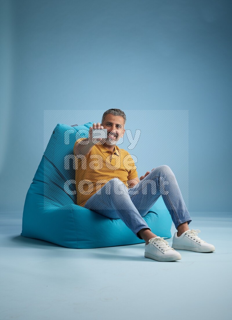 A man sitting on a blue beanbag and holding ATM card