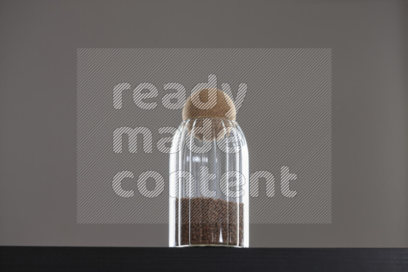 Brown lentils in a glass jar on black background