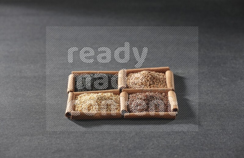 4 squares of cinnamon sticks full of black seeds, sesame, flaxseeds and mustard seeds on black flooring