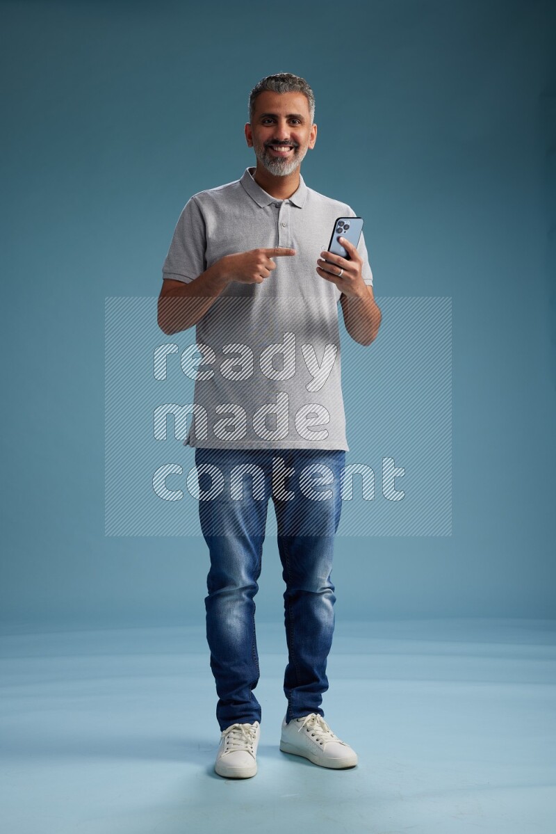 Man Standing texting on phone on blue background