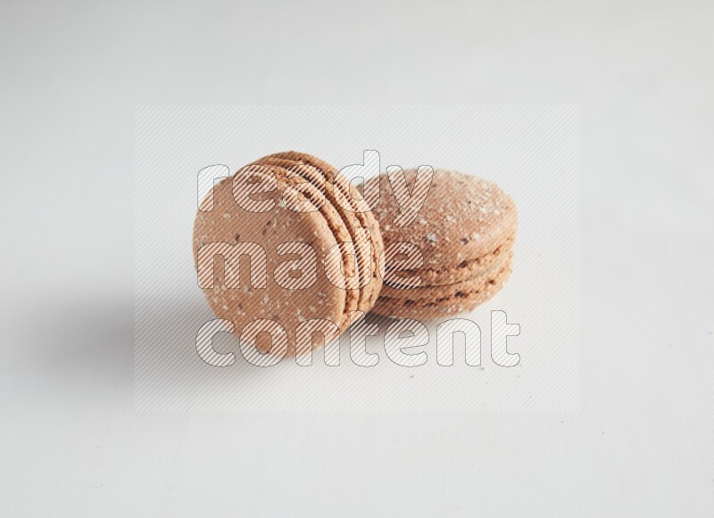45º Shot of two Brown Hazelnuts macarons on white background
