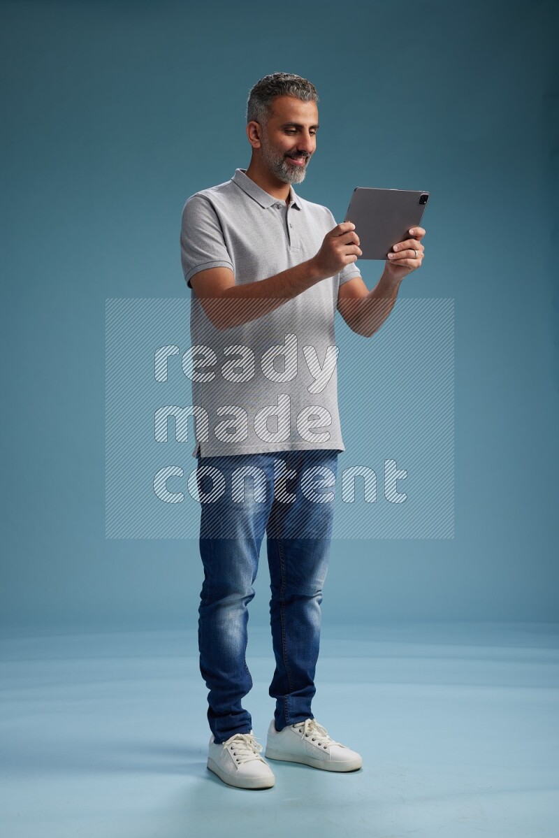 Man Standing working on tablet on blue background