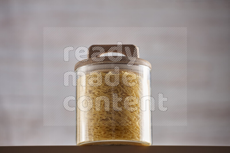 Raw pasta in glass jars on beige background