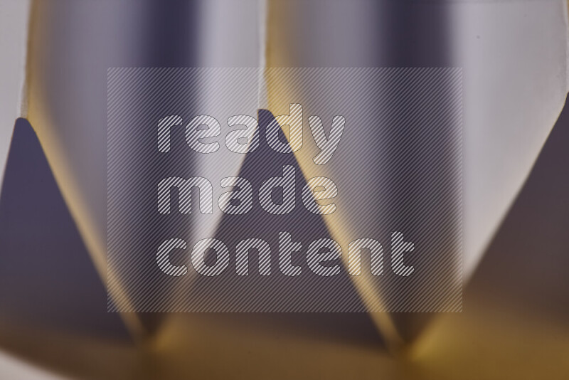 صورة مجردة مقربة تظهر طيات ورقية هندسية حادة بتدرجات اللون الأبيض مع درجات لونية دافئة