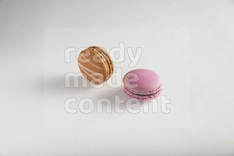 45º Shot of of two assorted Brown Irish Cream, and Purple Strawberry macarons on white background