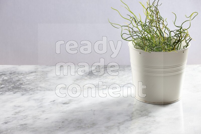 Green artificial plant in white pot on light grey marble background