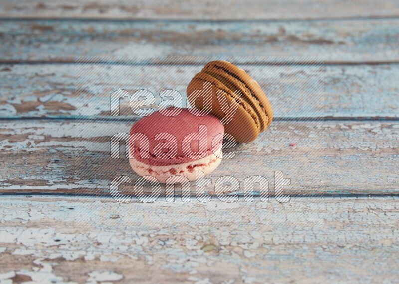 45º Shot of of two assorted Brown Irish Cream, and Pink Litchi Raspberry macarons on light blue background