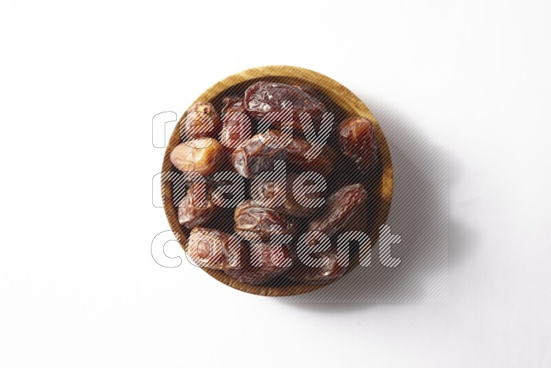 Dates in a wooden bowl on white background