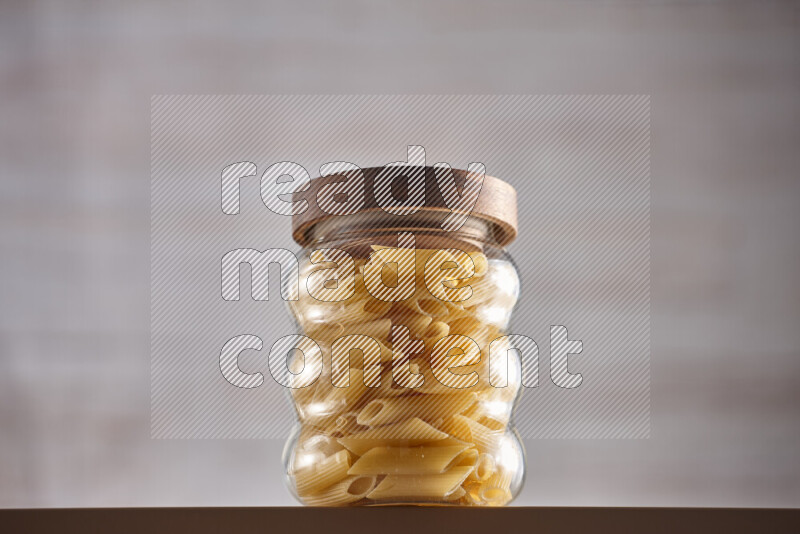 Raw pasta in glass jars on beige background