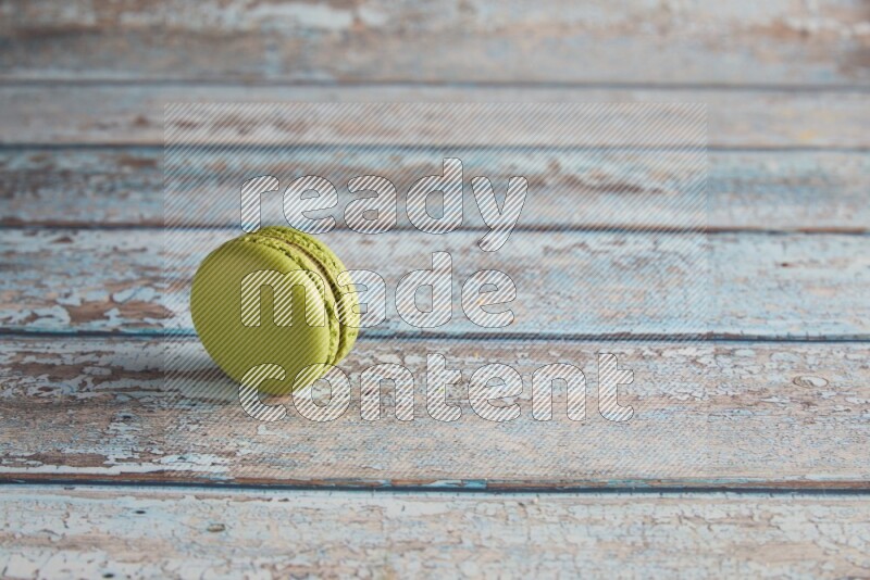 45º Shot of Green Pistachio macaron on light blue wooden background