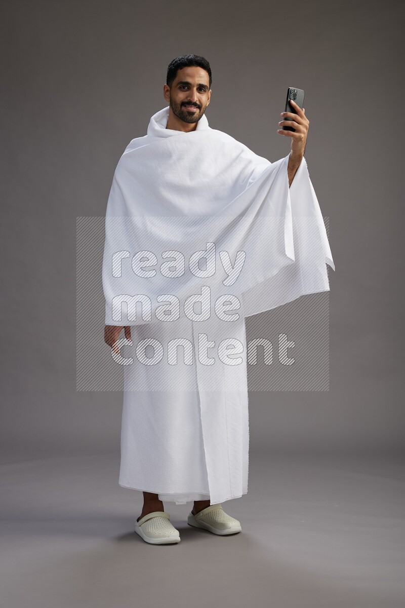 A man wearing Ehram Standing taking selfie on gray background