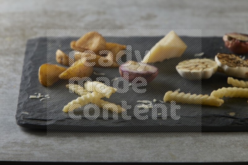 Mixed vegetables on a black stone serving platter on grey textured counter top