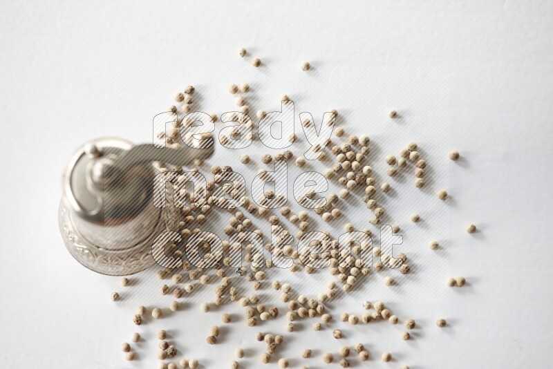 White pepper beads with a metal grinder on white flooring
