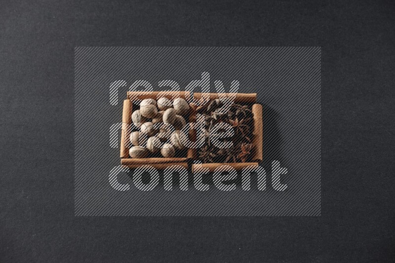 2 squares of cinnamon sticks full of nutmeg and star anise on black flooring