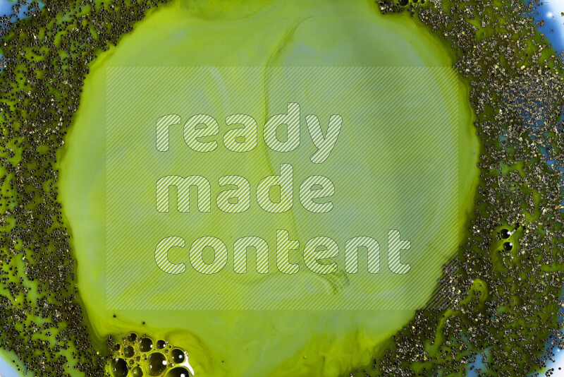 A close-up of sparkling gold glitter scattered on swirling blue and green background