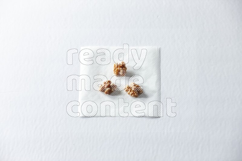 3 peeled walnuts on a piece of paper on a white background in different angles