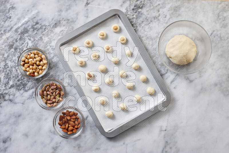 Ghoriba step by step with its ingredient, flour, powdered sugar, ghee and nuts on grey marble background