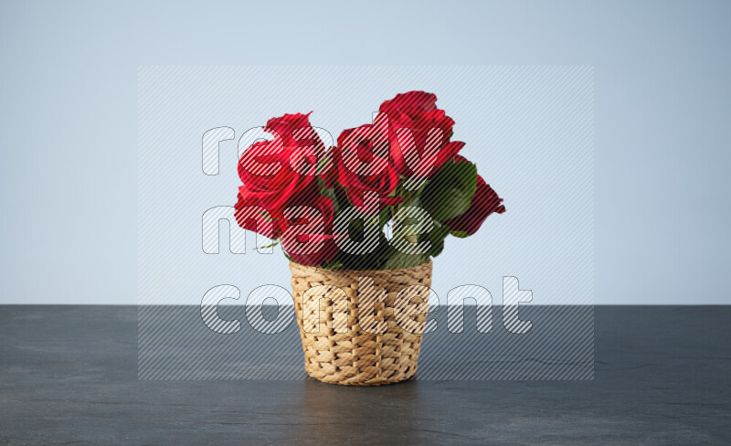 Vibrant red roses in a wicker basket on black marble background