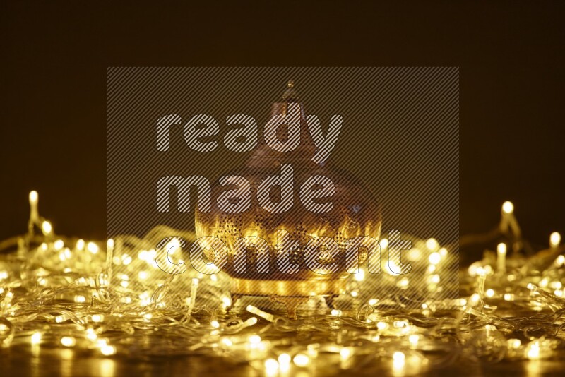 A traditional ramadan lantern surrounded by glowing fairy lights in a dark setup