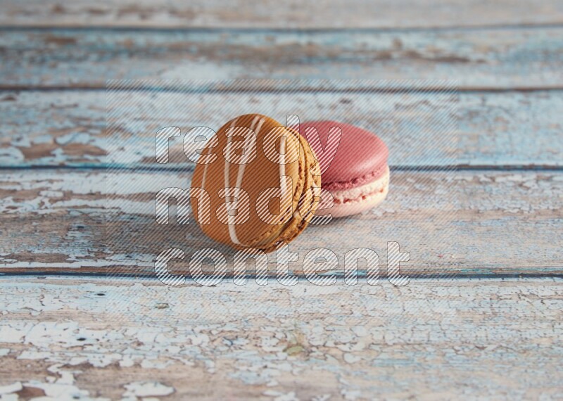 45º Shot of of two assorted Brown Irish Cream, and Pink Litchi Raspberry macarons on light blue background