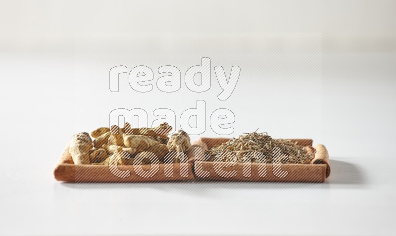 2 squares of cinnamon sticks full of cumin and turmeric fingers on white flooring