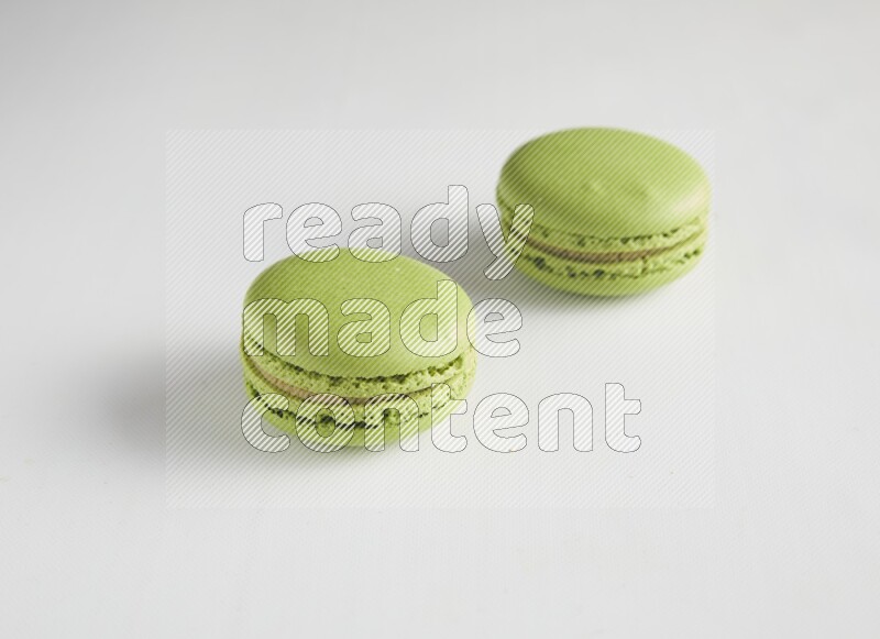 45º Shot of two Green Pistachio macarons on white background