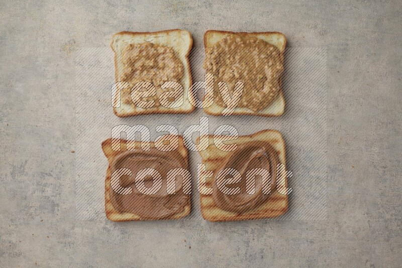Crunchy peanut butter on a toasted white toast and toasted white toast slices on a light blue textured background