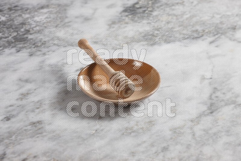 Multicolored pottery plate with wooden honey dipper in it on grey marble background